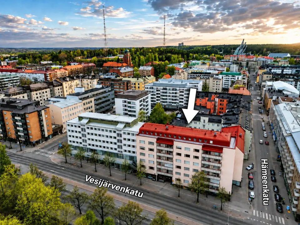 Kerrostalokohde kaupungin keskustassa auringonlaskussa, kohde osoitettu nuolella ja katunimet merkitty
